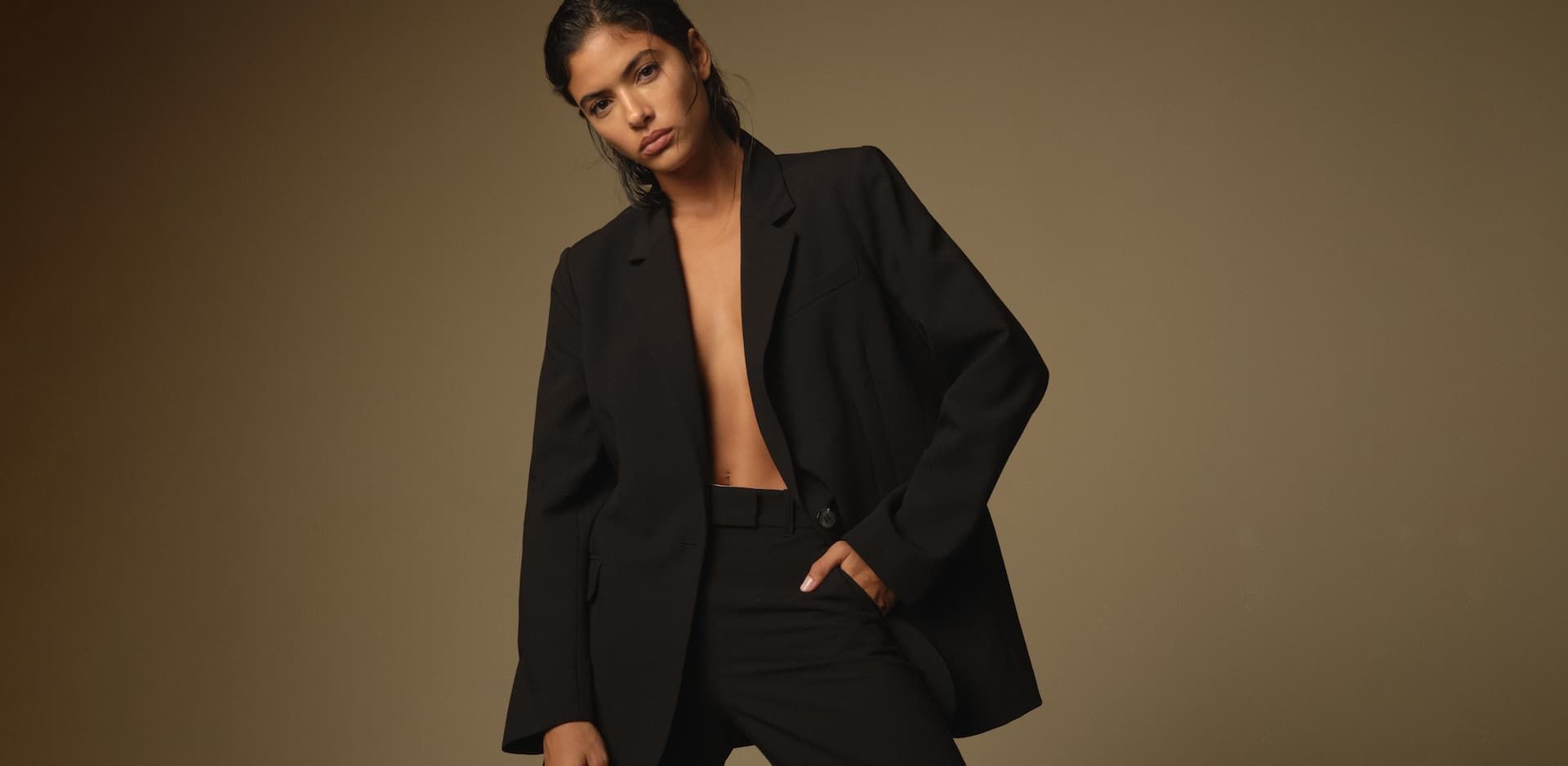 A model wears a black tailored blazer with black tailored pants.
