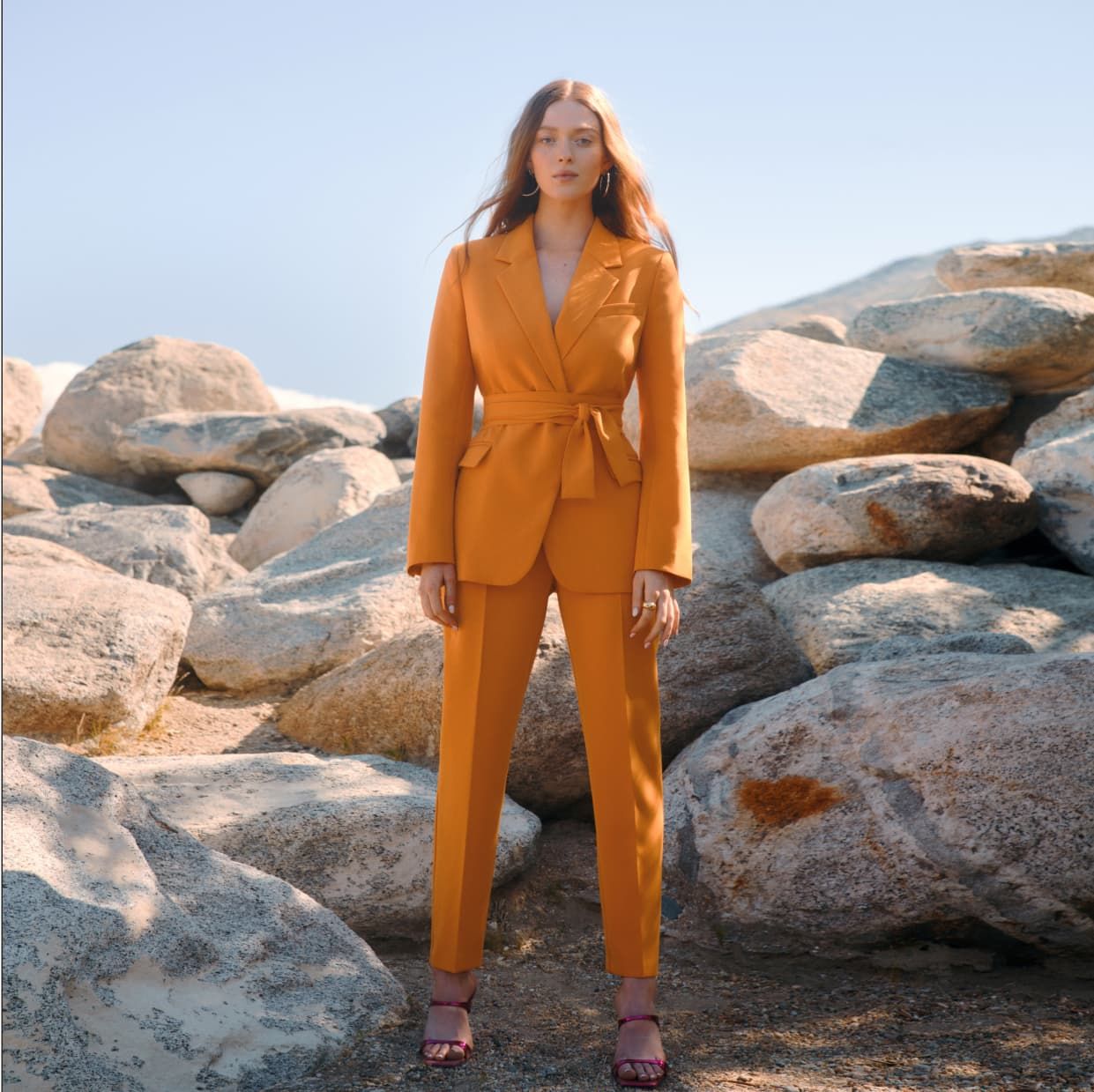 A model wears an orange belted blazer with matching orange pants.