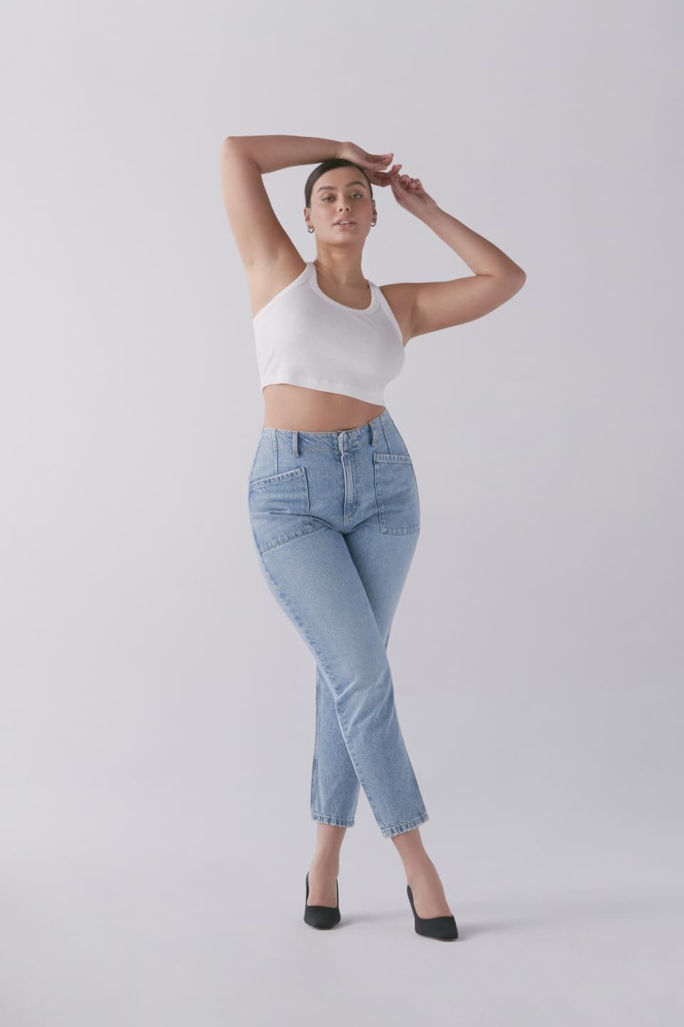 A model wears a white racer tank and blue mom jeans.