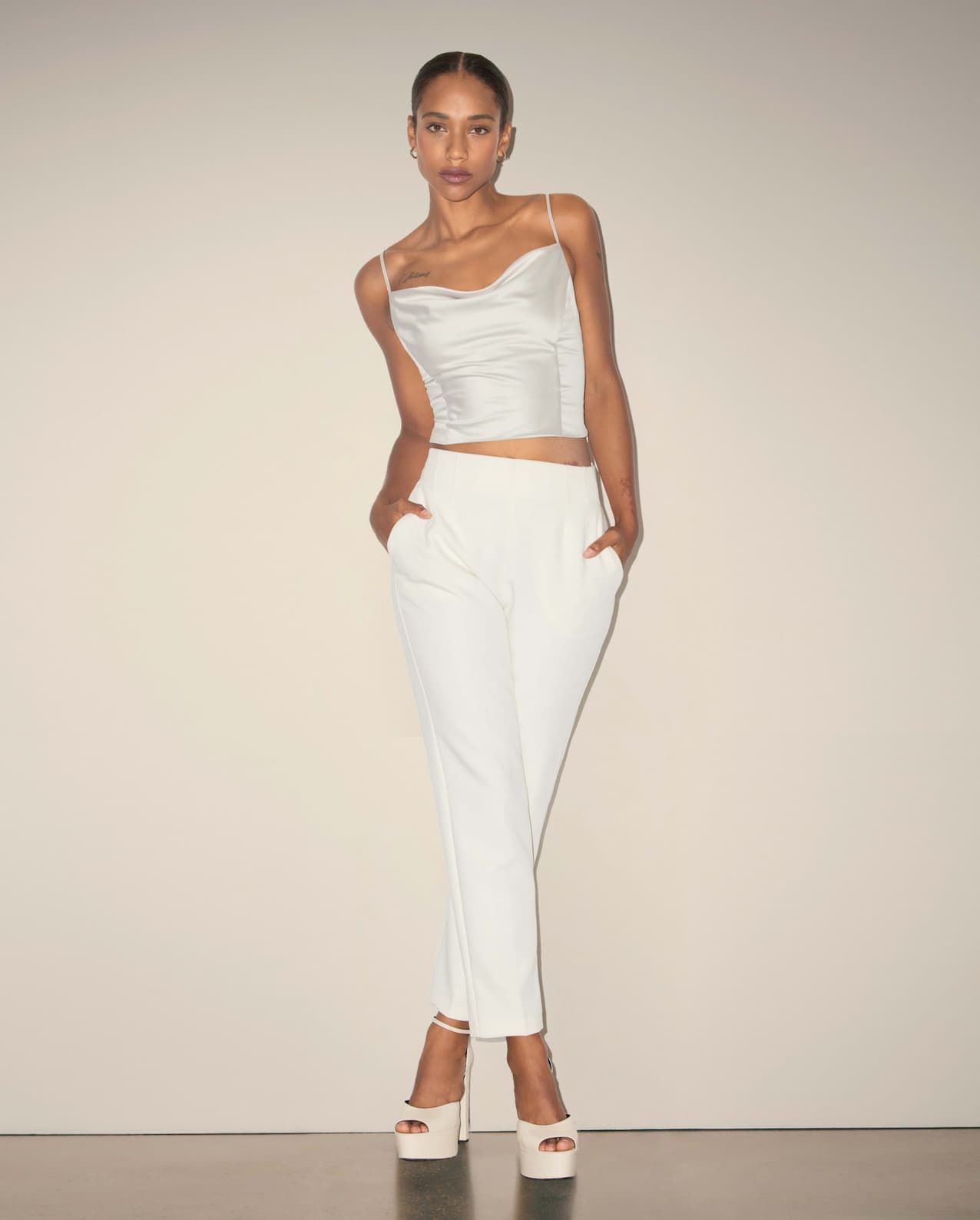 A model wears white slim leg pants with a white bustier top.