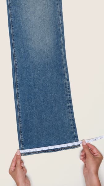 Place the measuring tape at the cuff of a pair of jeans.