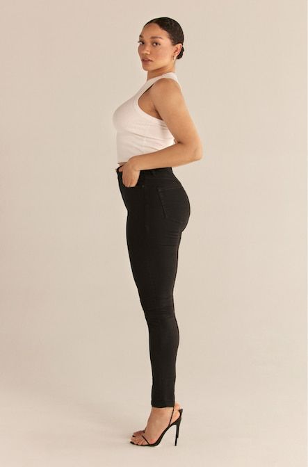 Une mannequin porte le jean skinny Kate en noir ultime avec une camisole blanche.