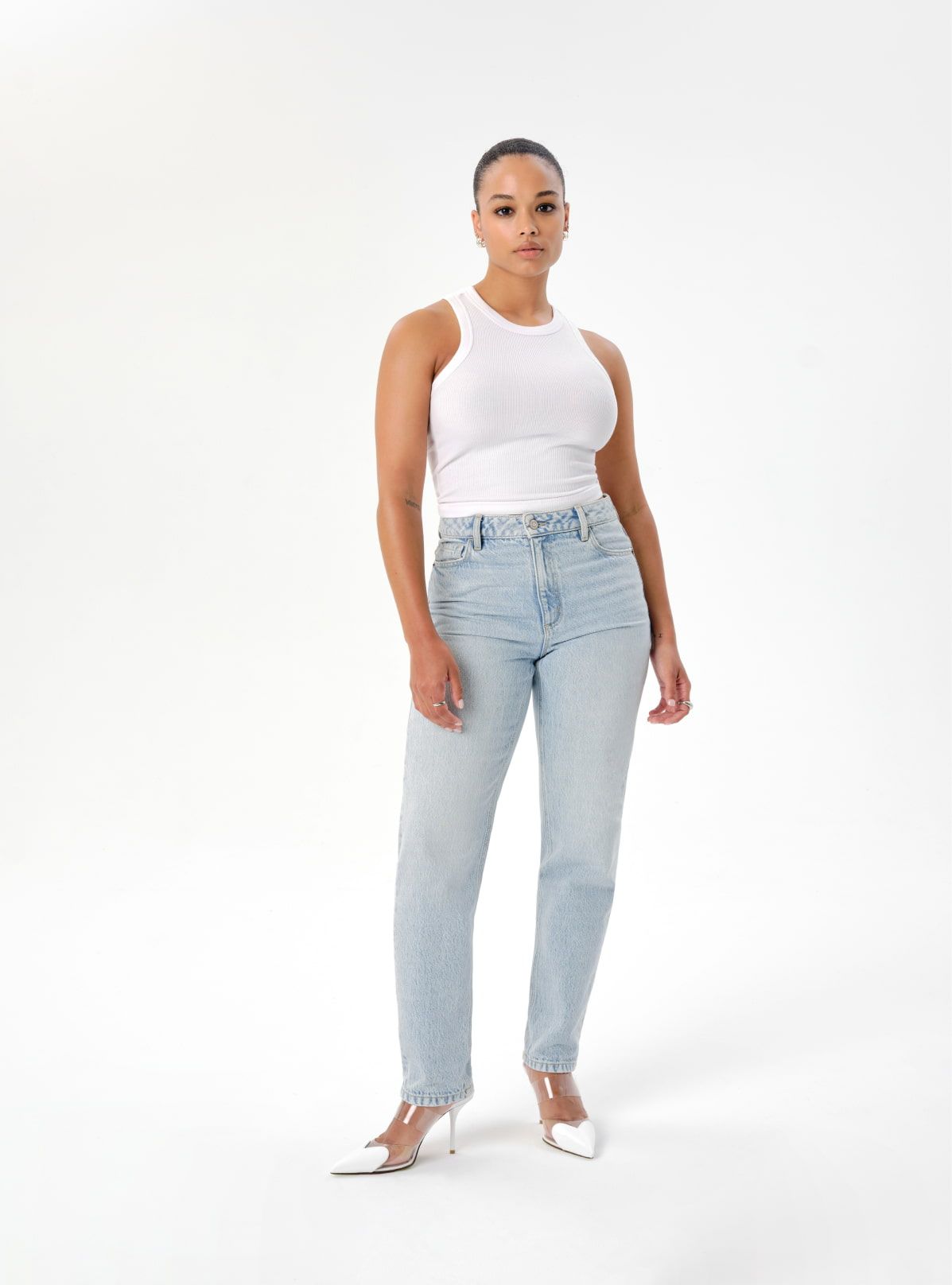 A model wears light blue mom jeans and a white racertank.