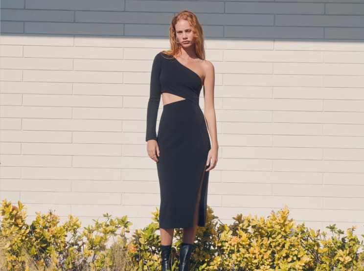 One model wears a black long sleeve mini dress with mesh front cut-outs and another model wears a black midi one-sleeve dress with a leg slit.