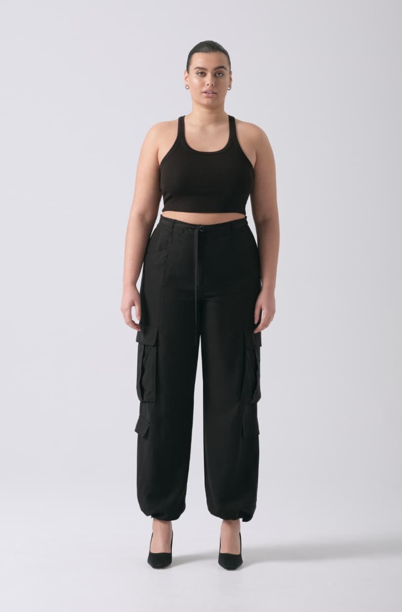 A model wears black cargo pants with a black tank top.