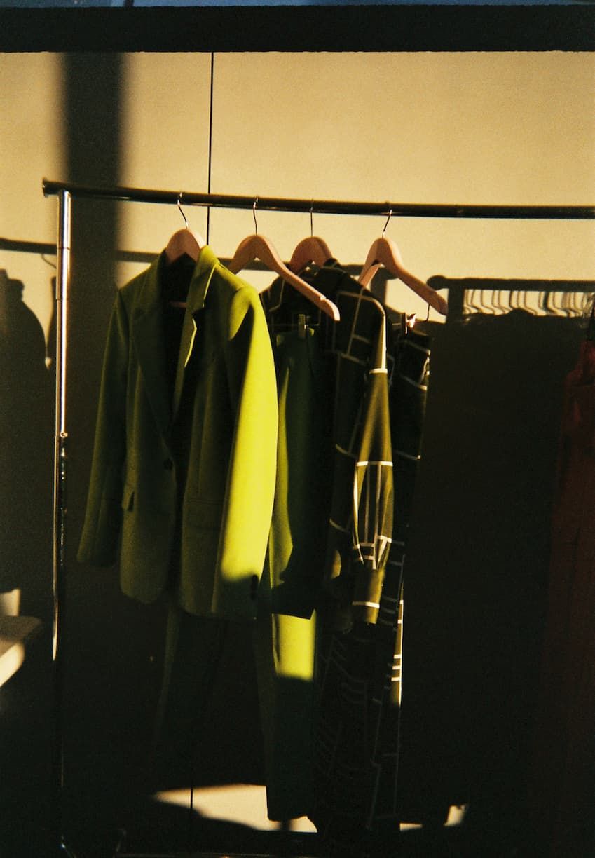 The Spring collection hangs on a rack featuring the green suit and a matching green printed set.