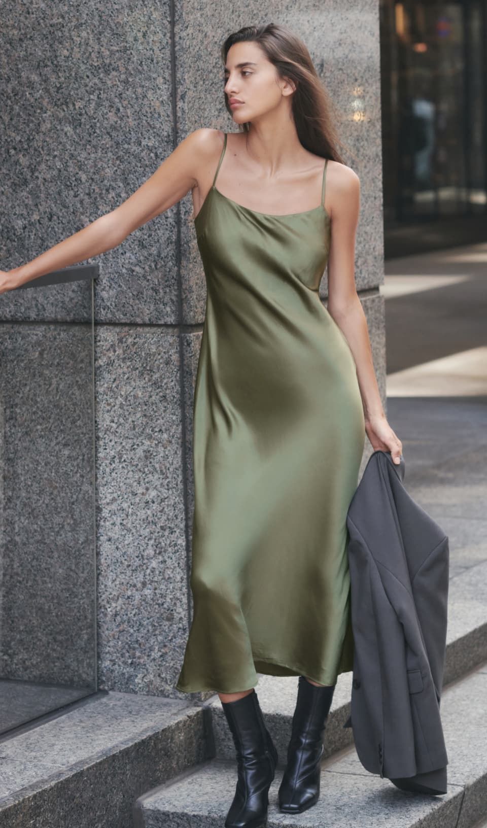 Une mannequin porte une robe midi sans manches en satin vert.