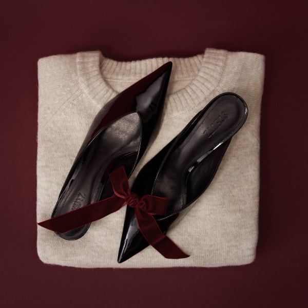 Black pointed toe mules and a beige cardigan.