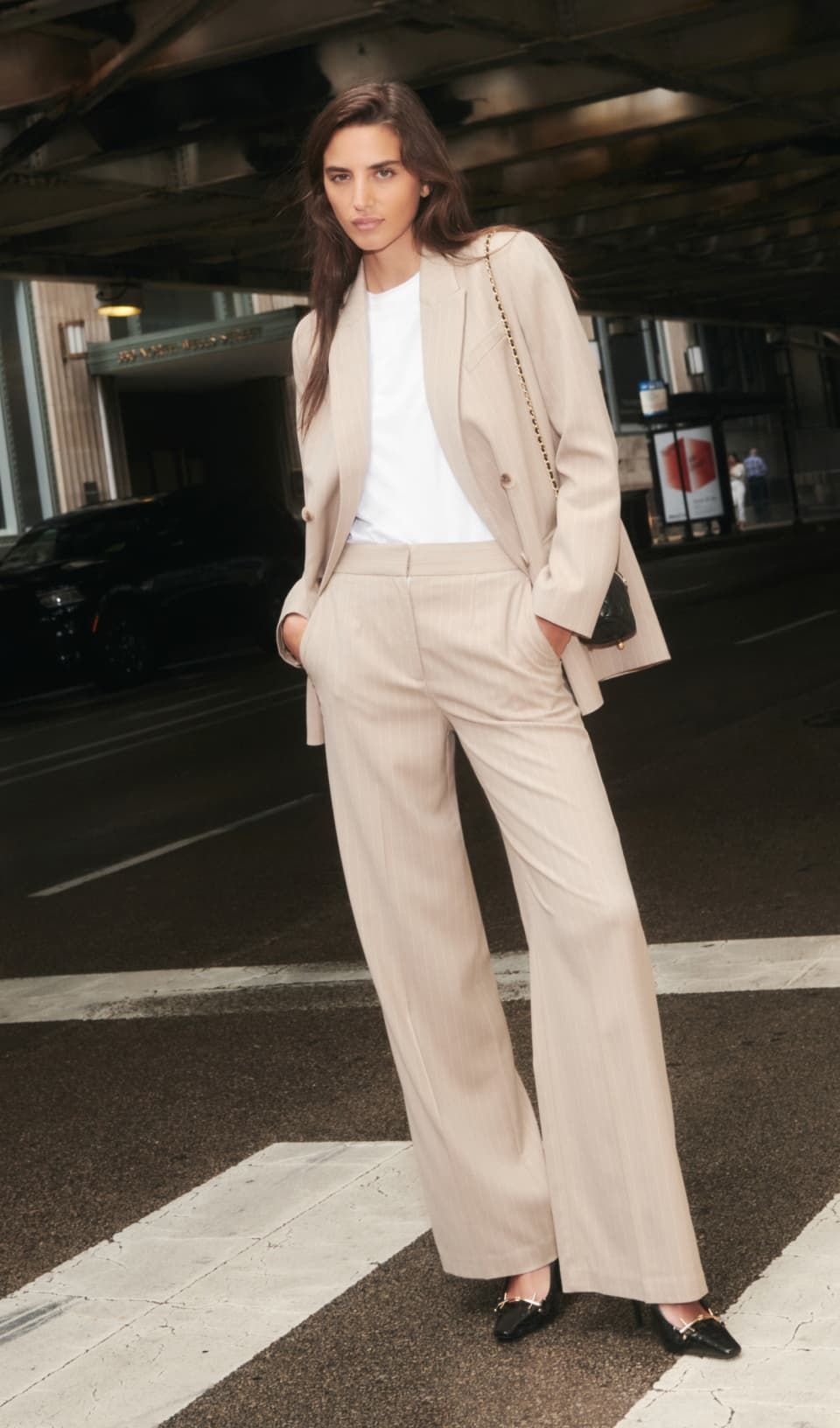 A model wears a beige pinstripe blazer with matching wide leg pants and a white top.