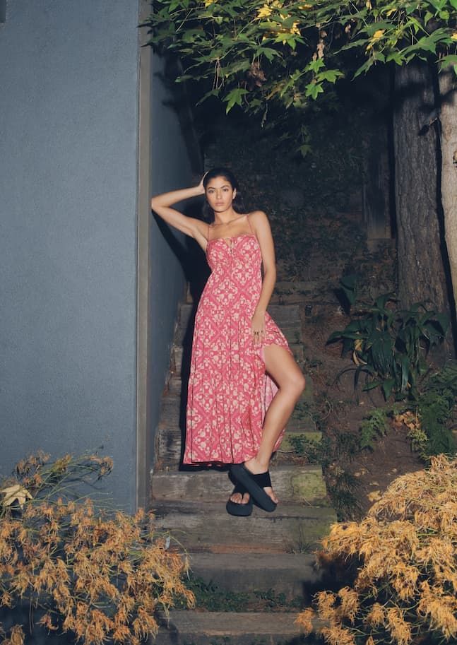 A model wears a pink printed maxi dress with a leg slit.