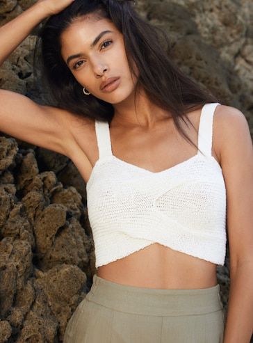 A model wears a knit white cross-front cropped tank with sage green linen shorts.