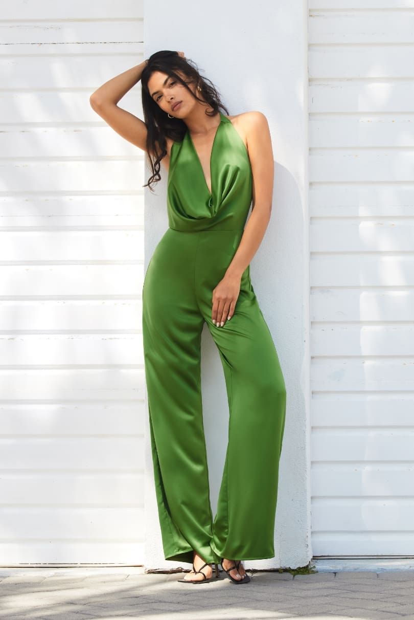 Une mannequin porte un ensemble une pièce en satin vert à col licou et jambe large.