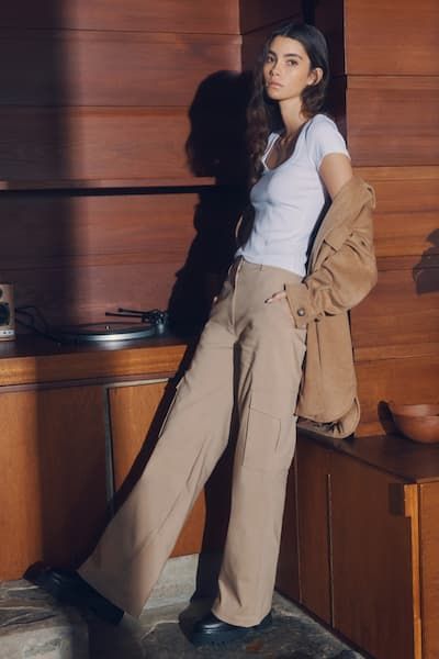 A model wears beige cargo pants with a white t-shirt.
