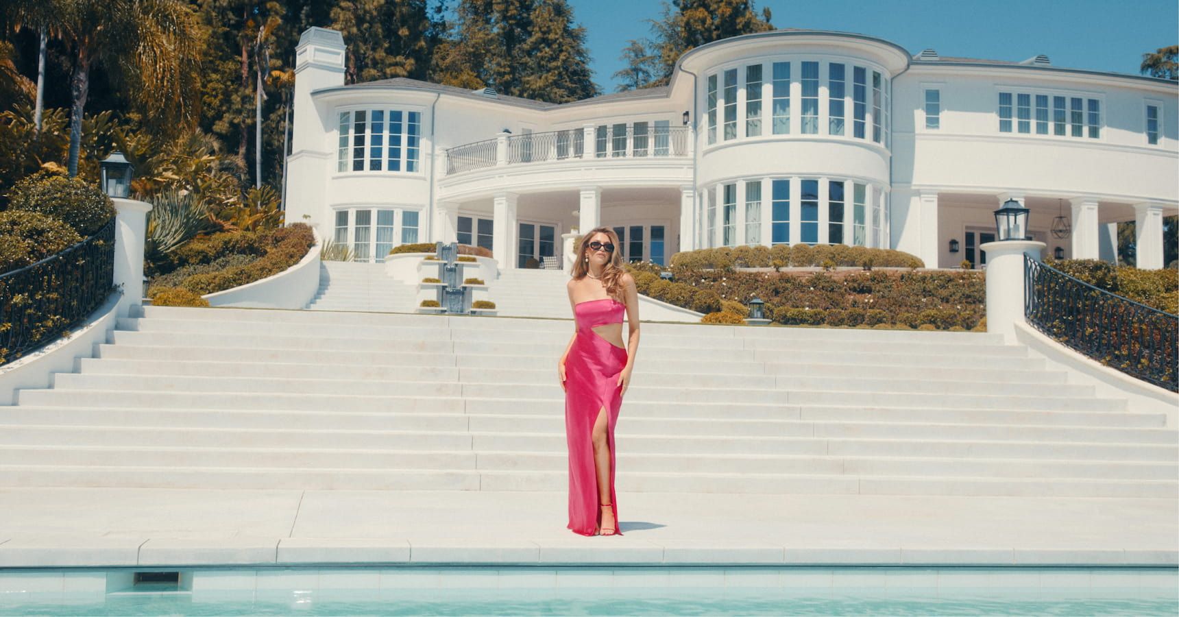 An influencer wears a pink satin strapless dress with a torso side cut-out.