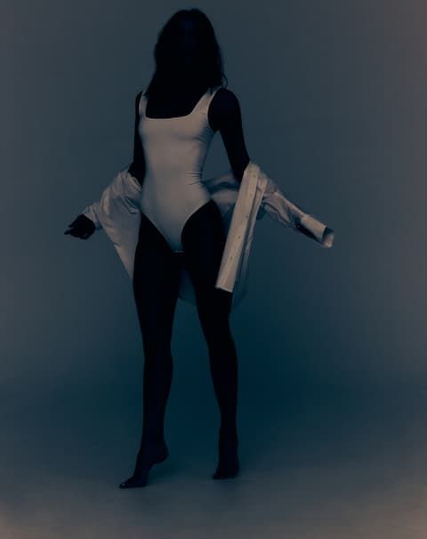 A model wears a white tank sculpt bodysuit.