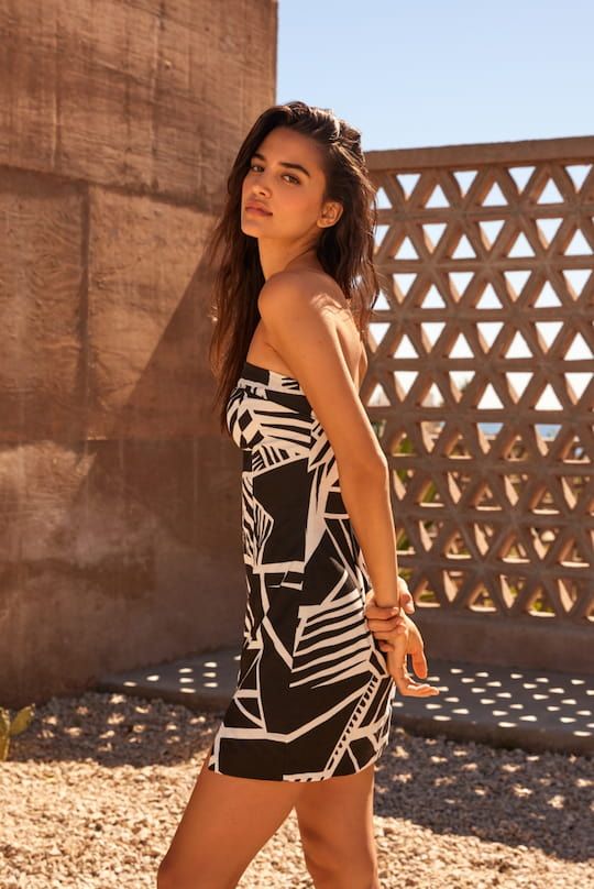 A model wears a black-and-white printed strapless linen dress.