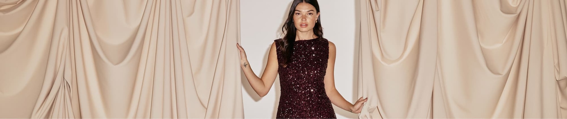 Model is wearing a burgundy sequin mini dress.