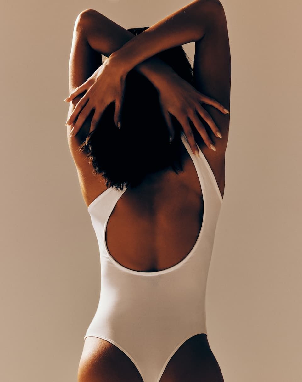 A model wears a white tank sculpt bodysuit.