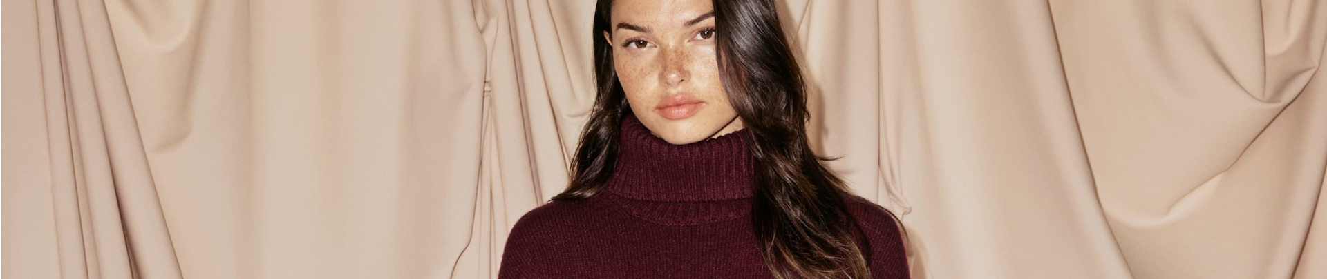 La mannequin porte un manteau en fausse fourrure beige.