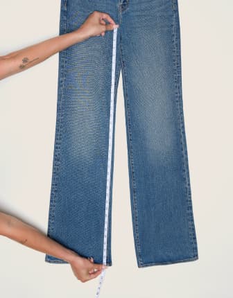 Place the measuring tape from the crotch seam to the hem on a pair of jeans.