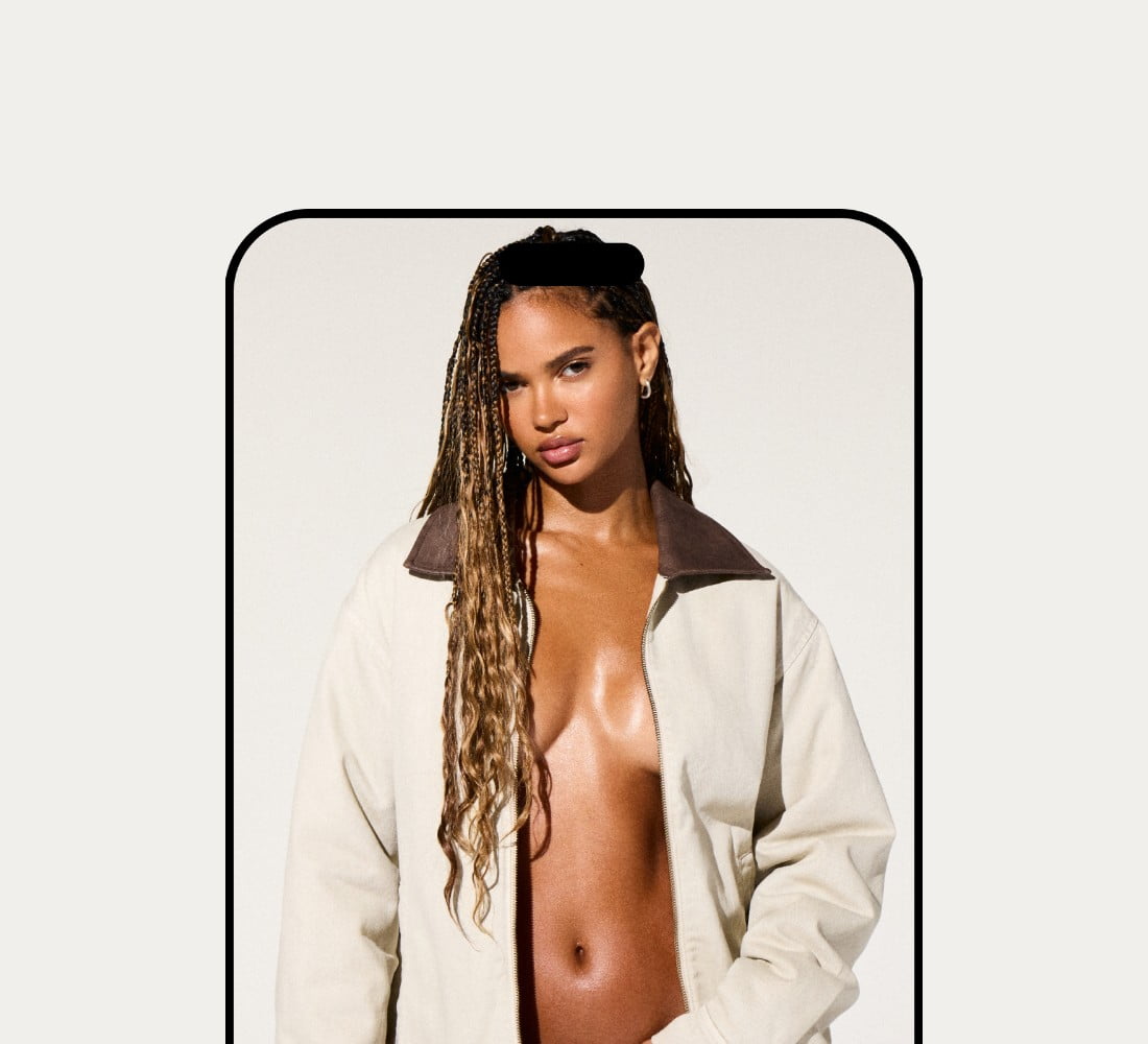 La mannequin prend la pose dans un blouson utilitaire blanc sans haut en dessous et un jean bleu pâle.