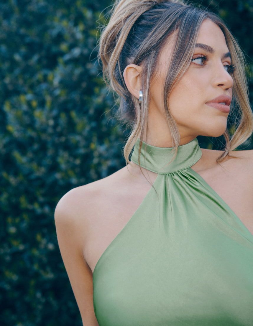 An influencer wears a green satin halter neckline dress with an open back.