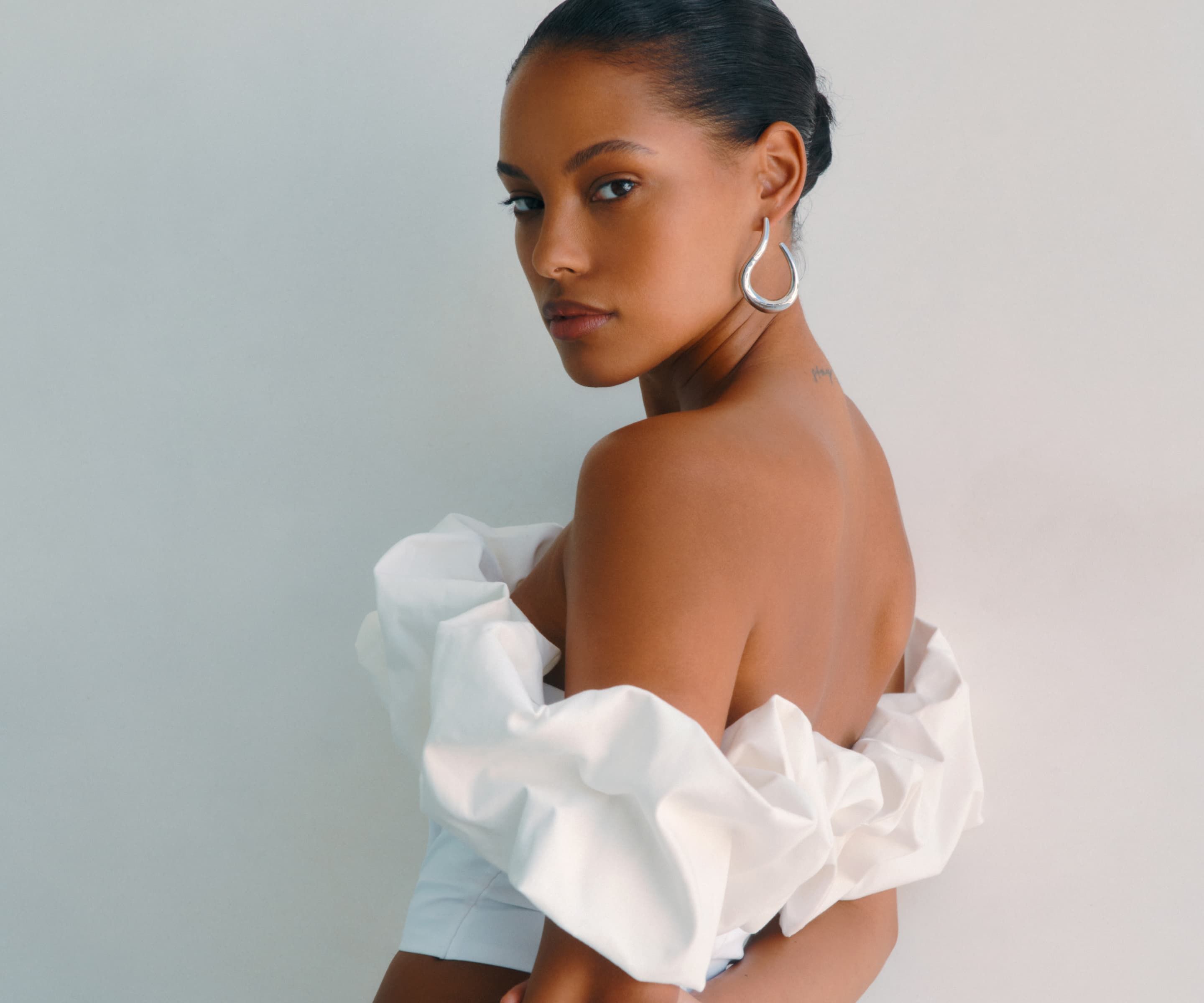 A model wears a white off-the-shoulder ruffled top.