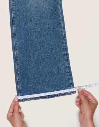 Place the measuring tape at the cuff of a pair of jeans.