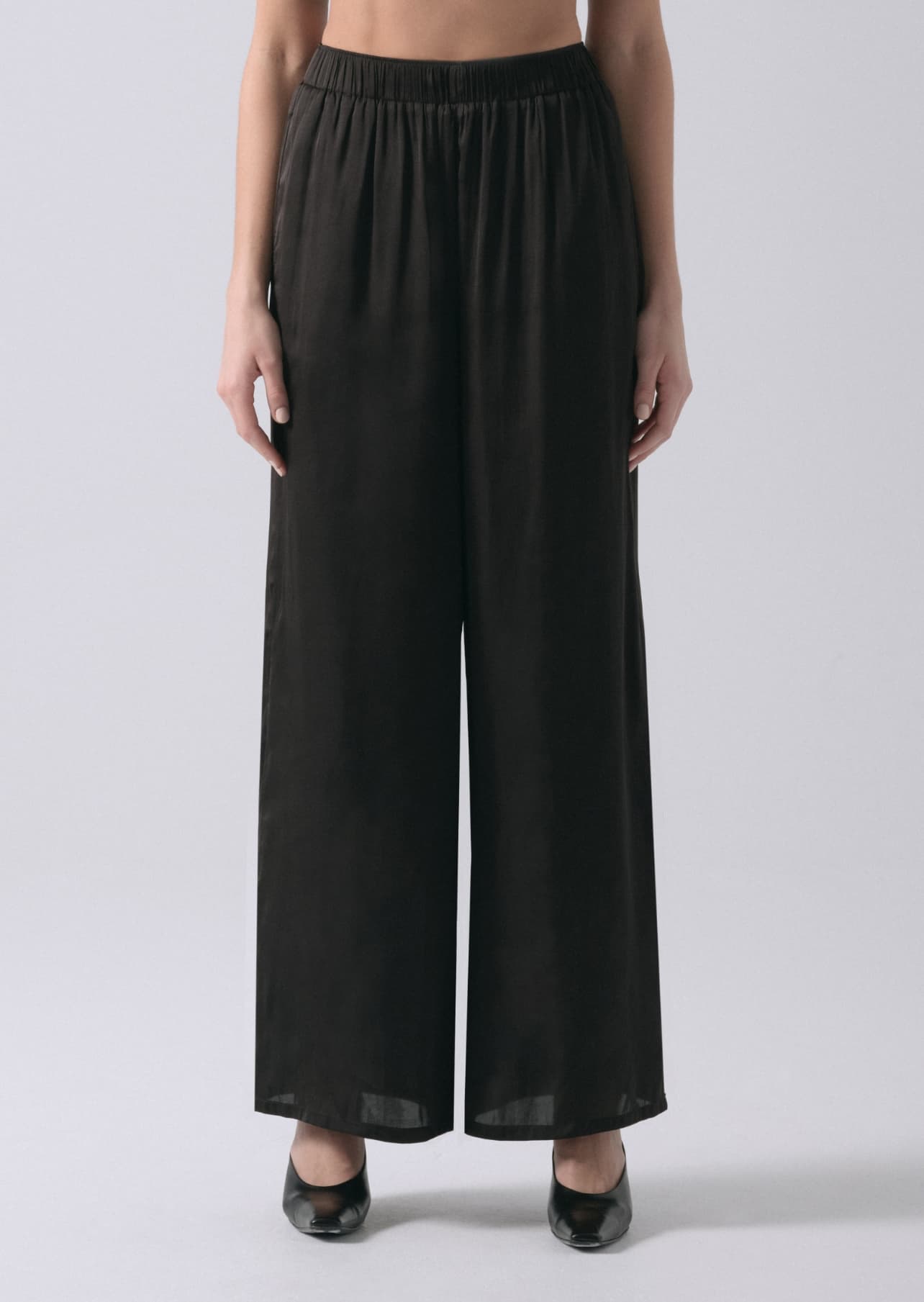 A model wears black wide leg satin pants.