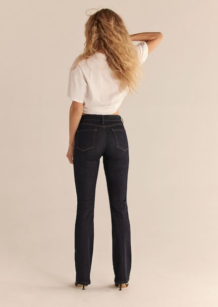 A model wears the Helena demi-bootcut jeans in dark indigo blue with a white t-shirt.