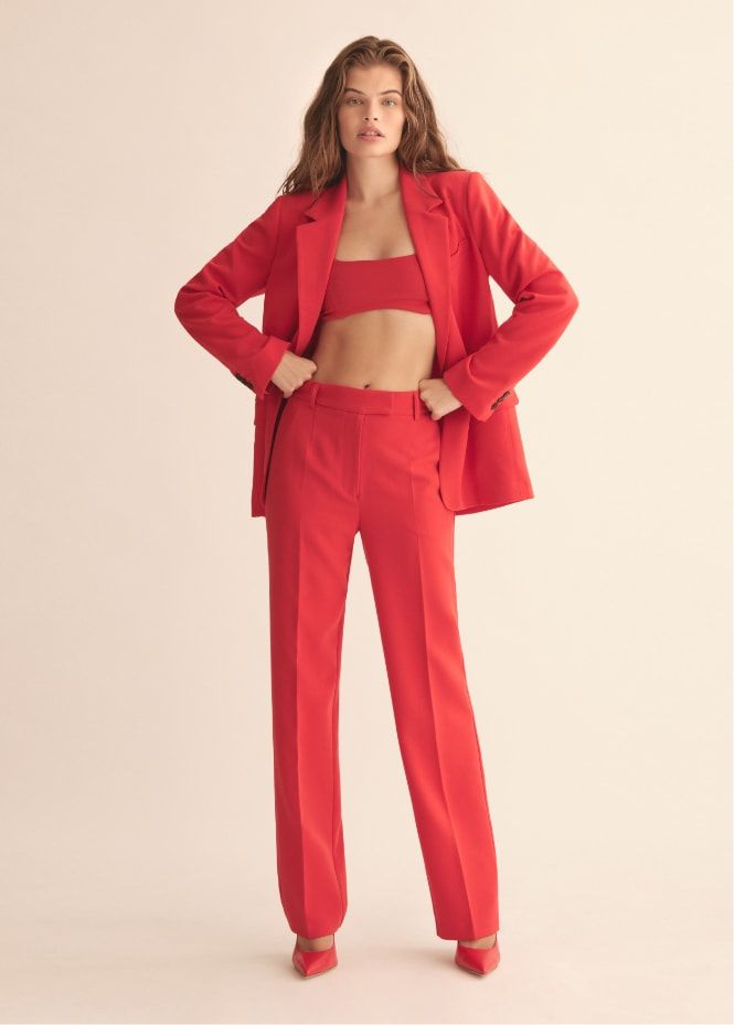 A model wears red straight pants with a red bra top and matching blazer.