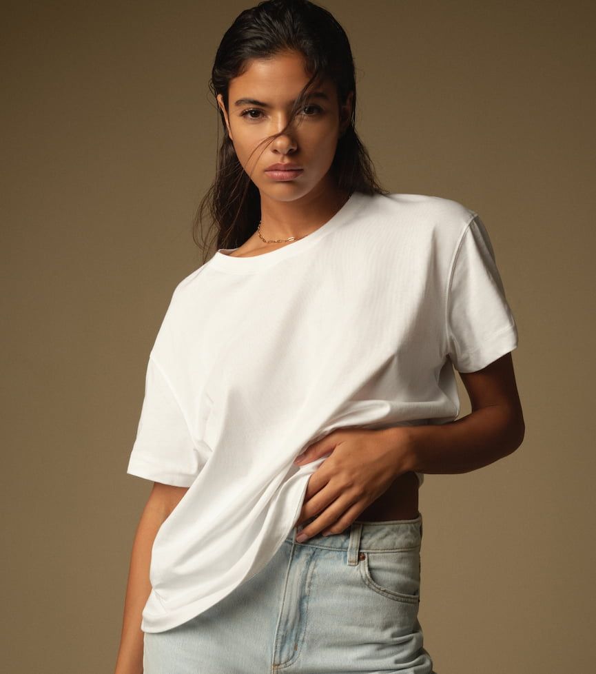 A model wears a white t-shirt with blue jeans.
