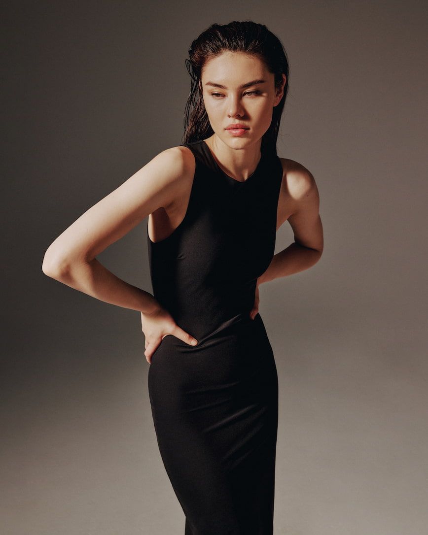 A model wears a sleeveless midi black sculpt'd dress.