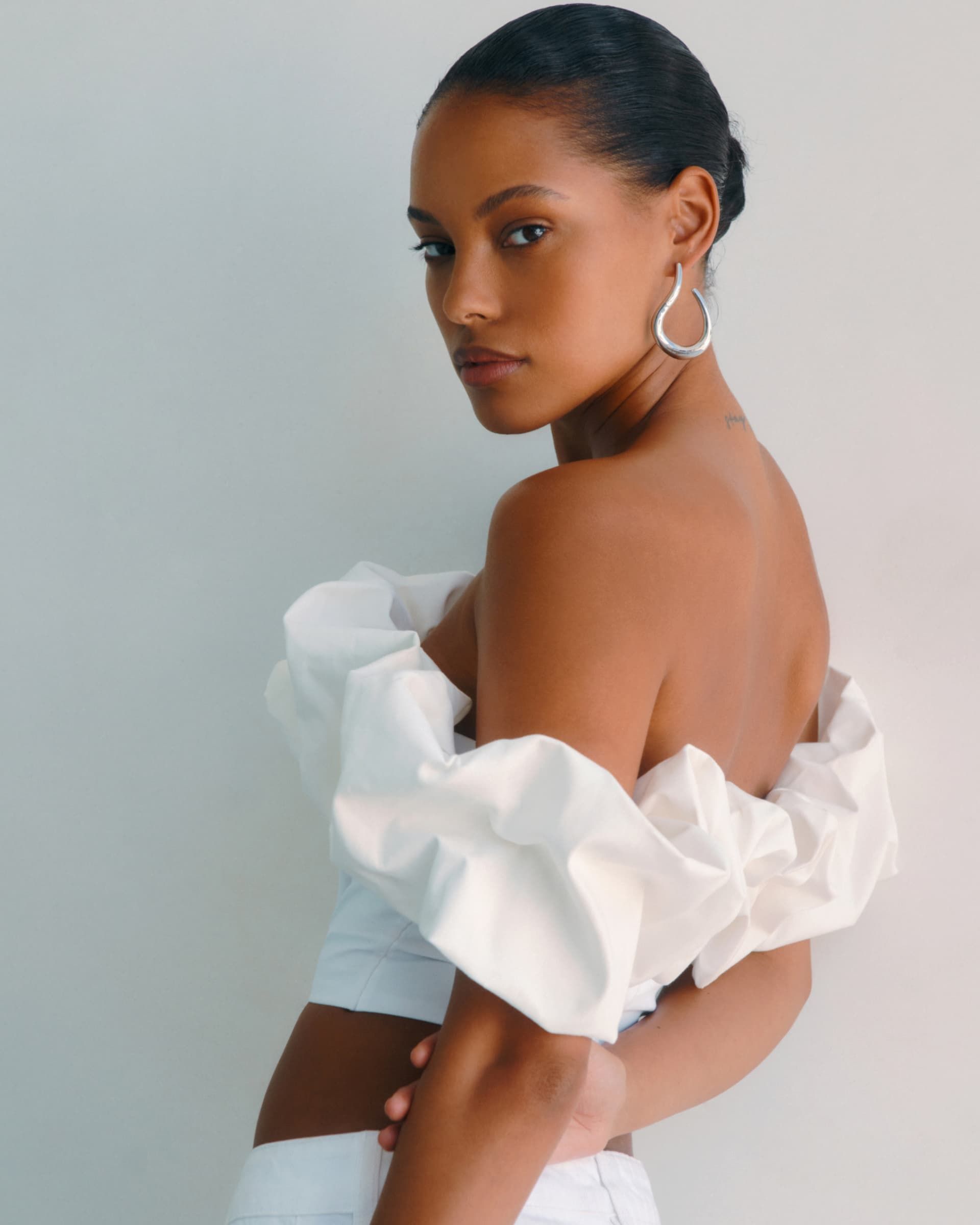 A model wears a white off-the-shoulder ruffled top.