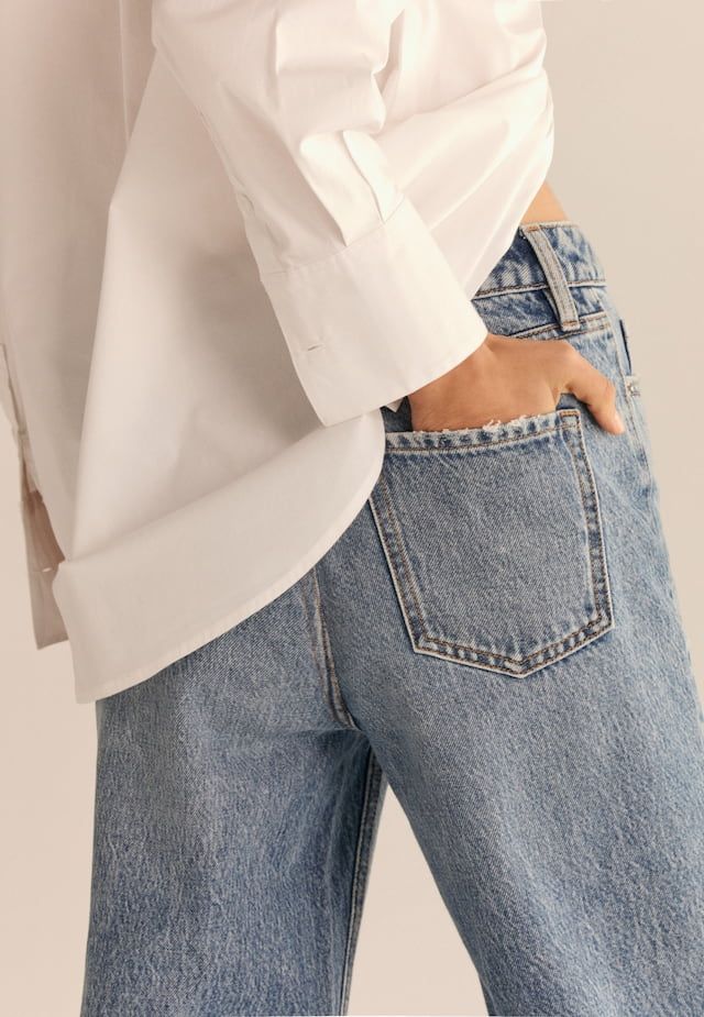 A model wears low-rise blue jeans with a white shirt.