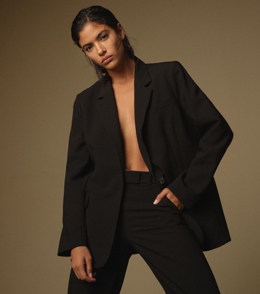 A model wears an open black blazer with matching black pants.