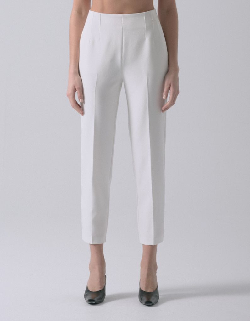 Une mannequin porte un pantalon blanc à jambe ajustée.