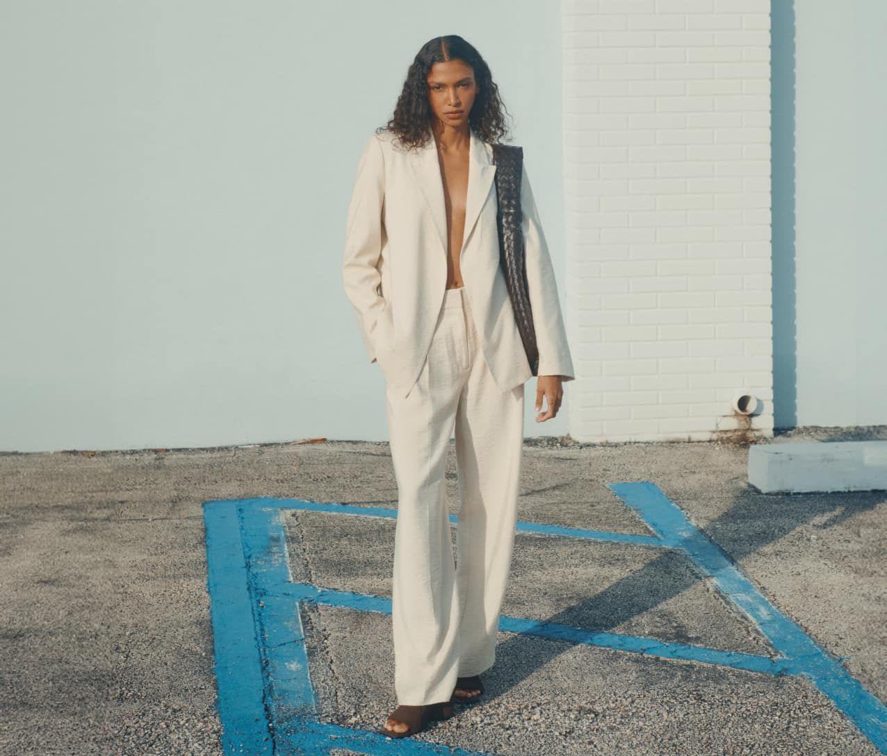 Model is wearing a matching white relaxed-fit suit.
