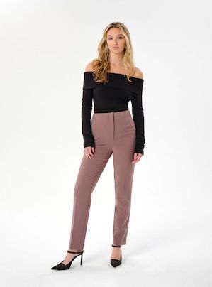 A model wears brown slim leg pants with a black long sleeve off-the-shoulder top.