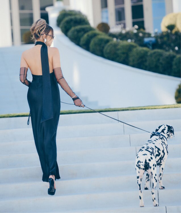 An influencer wears a black satin halter neckline dress with a leg slit.