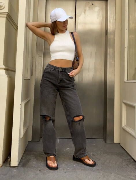 Model is wearing relaxed jeans and a white tank top.