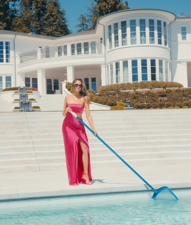 An influencer wears a pink satin strapless dress with a torso side cut-out.