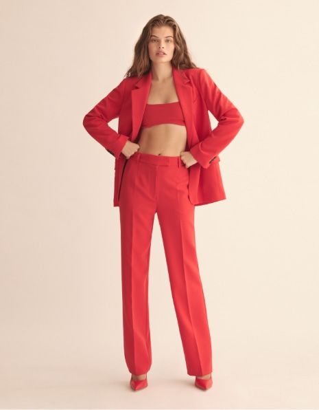 a model wears red straight pants with a red bra top and matching blazer.