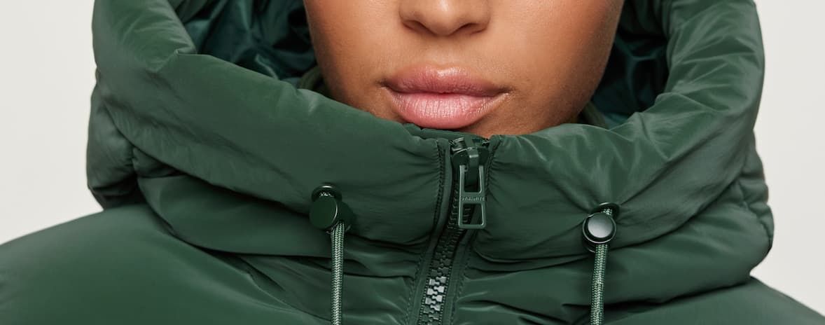 Model is wearing a green hooded Lustre Puff ™ jacket. 
