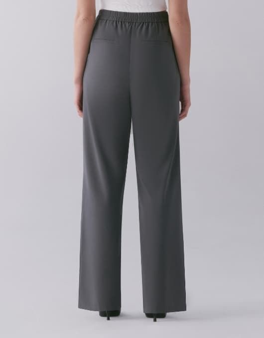 A model wears the Lila pleated straight leg pants - back view.