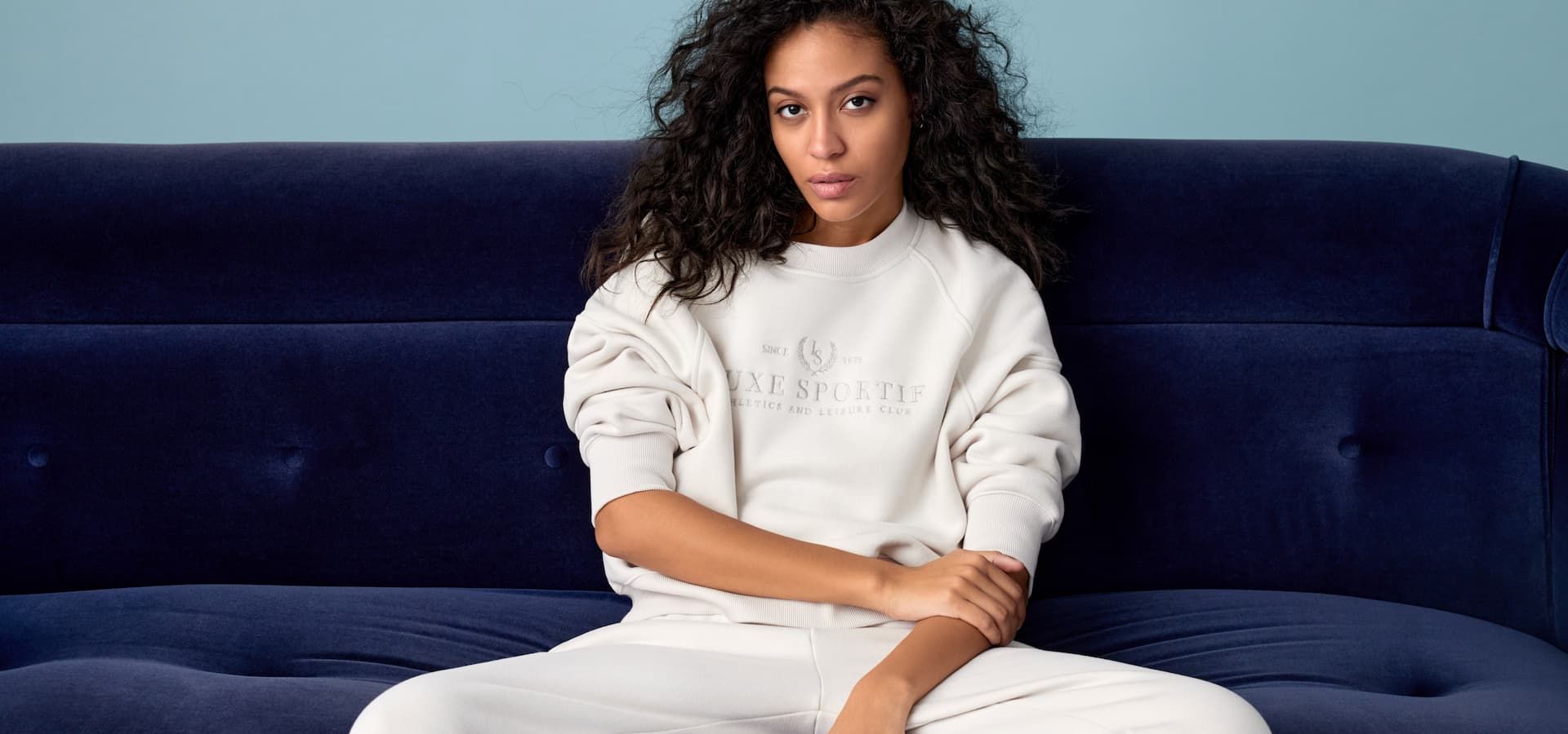 A model wears a beige crewneck with 'athletics & leisure club' embroidered with matching sweatpants.