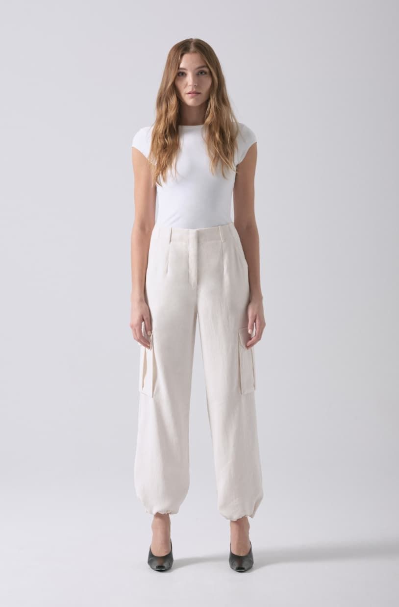A model wears white cargo parachute pants with a white t-shirt.