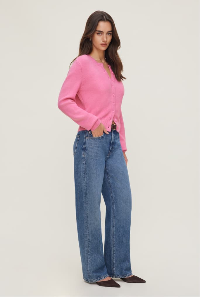 Model is wearing a pink cardigan and blue jeans.