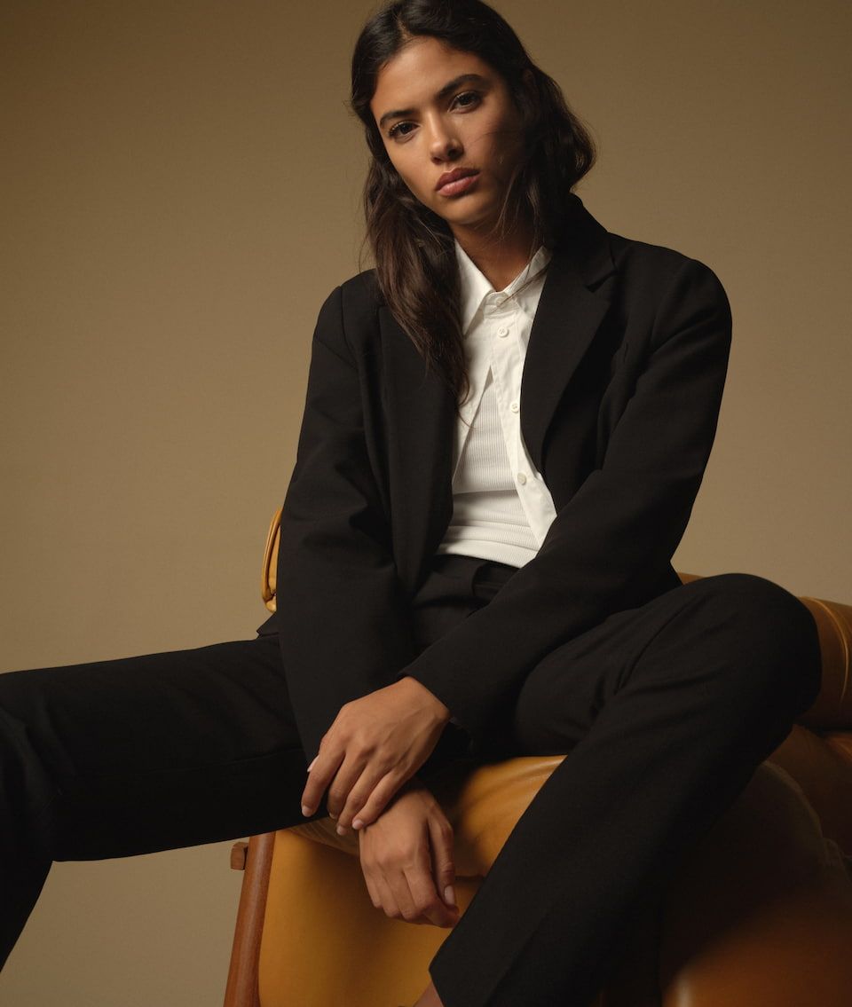 A model wears a white button-down shirt with a black blazer and matching black pants.