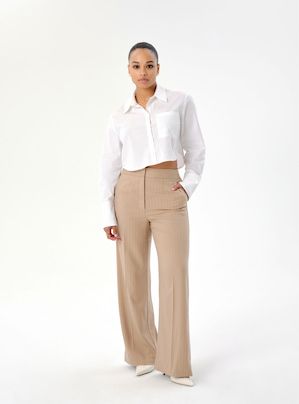 A model wears beige straight leg pants with a white button down shirt.